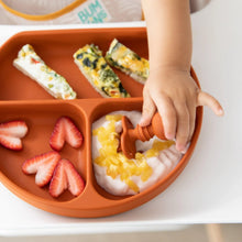 Load image into Gallery viewer, Close-up of a child's hand reaching for yogurt from a divided plate on a high chair tray with Bumkins Silicone Chewtensils®: Clay.