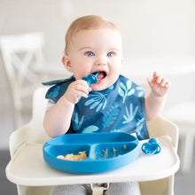 Load image into Gallery viewer, A baby in a high chair wearing a blue bib uses Bumkins Silicone Chewtensils®: Dark Blue to eat from a matching plate.
