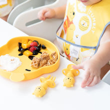 Load image into Gallery viewer, A child in a high chair with a yellow bib reaches for Bumkins Silicone Chewtensils®: Winnie The Pooh next to a bear-shaped plate with food.