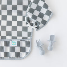 Load image into Gallery viewer, Bumkins Silicone Chewtensils®: Gray rest next to a gray & white checkered sleeved bib on a white background.