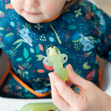 Load image into Gallery viewer, Close-up of an adult hand feeding a child in a dark blue bib with a Bumkins Silicone Chewtensils®: Green Jelly.