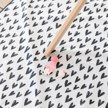 Load image into Gallery viewer, A Bumkins Silicone Chewtensils®: Pink Jelly rests on top of a black & white heart print mat with yogurt splatter under a high chair leg.