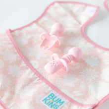 Load image into Gallery viewer, Bumkins Silicone Chewtensils®: Pink lay on top of a pink bib on a white background; one lays face down, showing sensory bumps on the back.