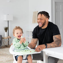 Load image into Gallery viewer, A man smiles at a table as a curly-haired child in a high chair enjoys baby-led weaning from a plate with Bumkins Silicone Chewtensils®: Sage.