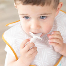 Load image into Gallery viewer, A toddler wearing a beige bib chews on a Bumkins Silicone Chewtensils®: Sand.