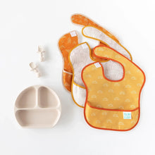 Load image into Gallery viewer, Bumkins Silicone Chewtensils®: Sand are displayed with a matching divided plate and three overlapping bibs on a white background.