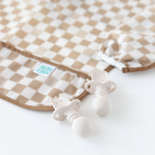 Load image into Gallery viewer, Close-up of Bumkins Silicone Chewtensils®: Sand on a white background next to a tan checkered bib.