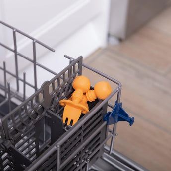 Bumkins Silicone Chewtensils®: Tangerine sits in the utensil compartment of an open dishwasher.
