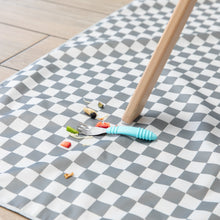 Load image into Gallery viewer, A Bumkins Spoon + Fork: Blue lays atop a gray & white checkered floor mat among scattered bits of fruit & veggies by a high chair leg.