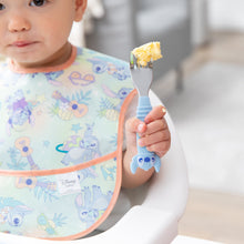 Load image into Gallery viewer, Close-up of a toddler in a pastel bib holding a Bumkins Spoon + Fork: Stitch with scrambled eggs.