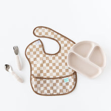 Load image into Gallery viewer, Bumkins Spoon + Fork: Sand sits next to the left of a tan checkered bib and a beige sectioned plate on a white background.