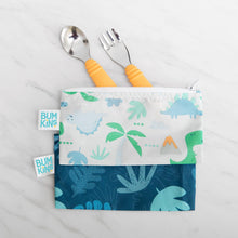 Load image into Gallery viewer, Bumkins Spoon + Fork: Tangerine peeks out from two dinosaur-print pouches on a marble background.