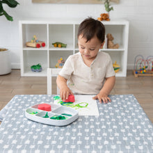 Load image into Gallery viewer, A boy uses Bumkins Silicone Grip Dish with Lid (5 Section): Marble to paint at a cloth-covered table in a bright playroom.