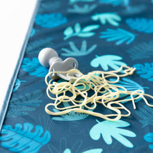 Load image into Gallery viewer, Close-up of a gray baby fork and spaghetti on top of Bumkins Splat Mat: Blue Tropic on a white background.