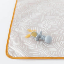Load image into Gallery viewer, Close-up of a baby spoon with applesauce on a Bumkins Splat Mat: Wander, on a white background.