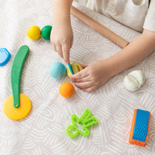 Load image into Gallery viewer, A child plays with colorful clay on a Bumkins Splat Mat: Wander.