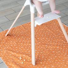 Load image into Gallery viewer, Bumkins Splat Mat: Grounded lays on a tiled floor beneath a baby in a high chair, sprinkled with pieces of food.
