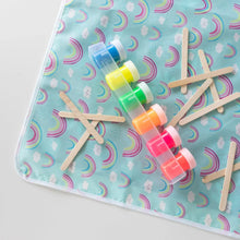 Load image into Gallery viewer, Close-up of Bumkins Splat Mat: Rainbows on a white background, with colorful paint pots and wooden craft sticks on top.