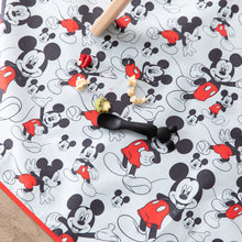 Load image into Gallery viewer, A black spoon and scattered food sits on top of Bumkins Splat Mat: Mickey Mouse on a floor under a chair.