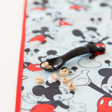 Load image into Gallery viewer, Close-up of a black spoon with cereal and milk on top of Bumkins Splat Mat: Mickey Mouse on a white background.