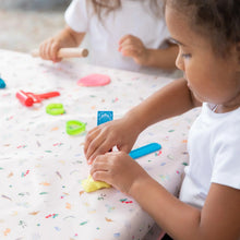 Load image into Gallery viewer, Two kids mold colorful clay on a table covered with Bumkins Splat Mat: Princess Magic for easy cleaning.
