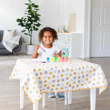 Load image into Gallery viewer, A child paints happily on a Bumkins Splat Mat: Winnie and Friends, ensuring easy spill and splash cleanup in the bright living room.