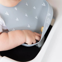 Load image into Gallery viewer, Close-up of a baby in a Bumkins Silicone Bib: Hearts reaching for food in the front pocket.