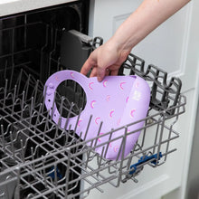 Load image into Gallery viewer, A person places Bumkins Silicone Bib: Rainbows in the top rack of an open dishwasher.