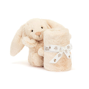 A cream-colored Jellycat Soother Luxe Bunny Willow plush holding a matching baby toy blanket tied with a branded ribbon.