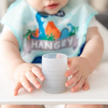 Load image into Gallery viewer, Close-up of a baby in a high chair wearing a dinosaur bib holding a Bumkins Silicone Starter Cup: Gray.