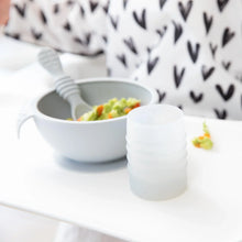 Load image into Gallery viewer, Bumkins Silicone Starter Cup: Gray sits in front of a gray bowl with mashed avocado on a white high chair tray.
