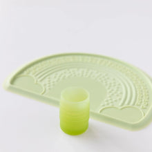 Load image into Gallery viewer, Bumkins Silicone Starter Cup: Sage sits in front of a green placemat on a white background.