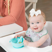 Load image into Gallery viewer, A smiling baby in a high chair wearing a Bumkins Starter Bib 2 Pack: Floral & Lace holds a blue bowl as an adult sits nearby.