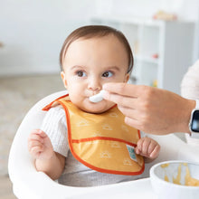 Load image into Gallery viewer, An adult feeds a baby with a spoon while they sit in a high chair, wearing a yellow Bumkins Starter Bib 2 Pack: Sunshine and Grounded.