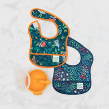 Load image into Gallery viewer, Bumkins Starter Bib 2 Pack: Jungle & Animal Prints lays overlapped on a marble background, with an orange bowl and spoon set nearby.