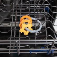 Load image into Gallery viewer, Bumkins Silicone Teething Charms: Orange sits in the top rack of an open dishwasher.