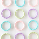 Multiple sets of Bumkins Silicone Teething Rings 4 Pack: Spring are neatly laid out on a white background.
