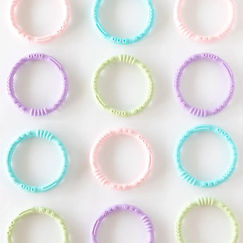 Multiple sets of Bumkins Silicone Teething Rings 4 Pack: Spring are neatly laid out on a white background.