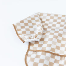 Load image into Gallery viewer, Close-up of Bumkins Sleeved Bib: Sand Check on a white background, with focus on the white elastic cuff on the sleeve.