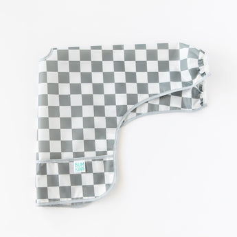 Bumkins Sleeved Bib: Charcoal Check lays folded lengthwise on a white background.