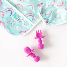 Load image into Gallery viewer, Close-up of dark pink toddler utensils near Bumkins Sleeved Bib: Rainbows on a white background.