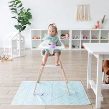 Load image into Gallery viewer, A toddler in a high chair wears a Bumkins Sleeved Bib: Rainbows, eating from a purple bowl in a bright playroom with toys.