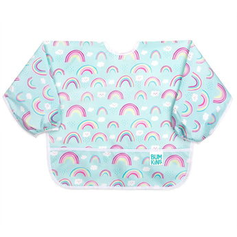 Bumkins Sleeved Bib: Rainbows is made of light blue waterproof fabric with a rainbow and cloud pattern, white trim, and front pocket.