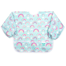 Load image into Gallery viewer, Bumkins Sleeved Bib: Rainbows is made of light blue waterproof fabric with a rainbow and cloud pattern, white trim, and front pocket.
