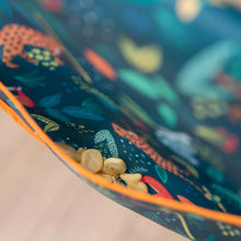 Load image into Gallery viewer, Close-up of Bumkins Sleeved Bib: Jungle with crackers in the pocket.