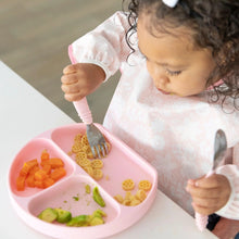 Load image into Gallery viewer, A toddler enjoys pasta, carrots, and avocado from a pink plate while using utensils and wearing a Bumkins Sleeved Bib: Lace.