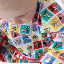 Load image into Gallery viewer, A child in Bumkins Sleeved Bib: Mickey & Friends Check Mates with drops of yogurt on the front of the bib.