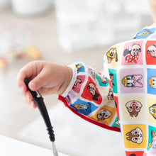 Load image into Gallery viewer, Baby's hand holding a spoon, wearing Bumkins Sleeved Bib: Mickey & Friends Check Mates in a bright room.
