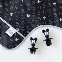 Load image into Gallery viewer, Close-up of Bumkins Sleeved Bib: Mickey Mouse Icon Black + White on a white background, with Mickey Mouse-shaped utensils close by.