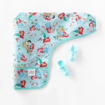 Bumkins Sleeved Bib: Ariel lays folded next to blue baby utensils on a white background.